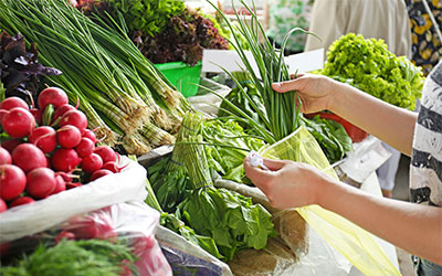 picture of a person shopping for vegetables using a reusable veggie bag